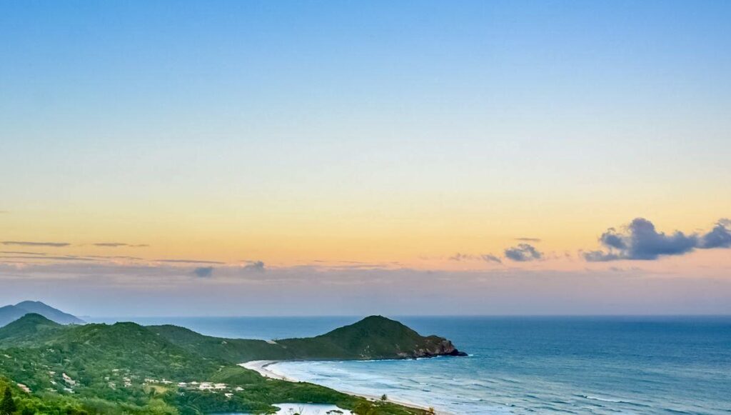 A breathtaking view of Praia do Rosa, known for its clear waters, golden sands, and scenic beauty, located in Santa Catarina, Brazil.
