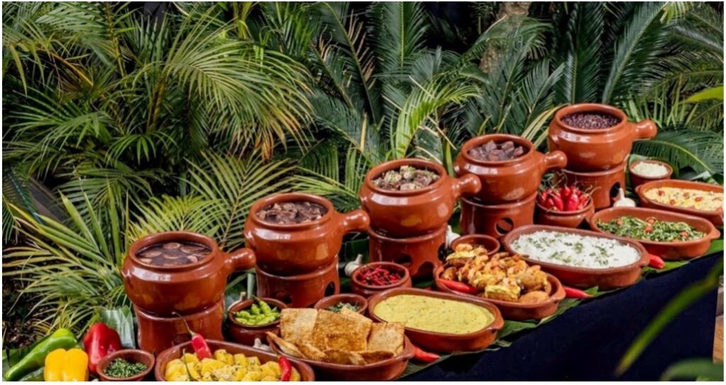Brazilian Feijoada served with rice, collard greens, and orange slices.