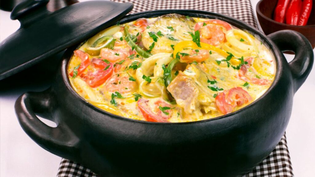 A bowl of Moqueca Baiana, a rich and aromatic seafood stew from Bahia, featuring fish, shrimp, coconut milk, and the distinctive taste of dendê oil.