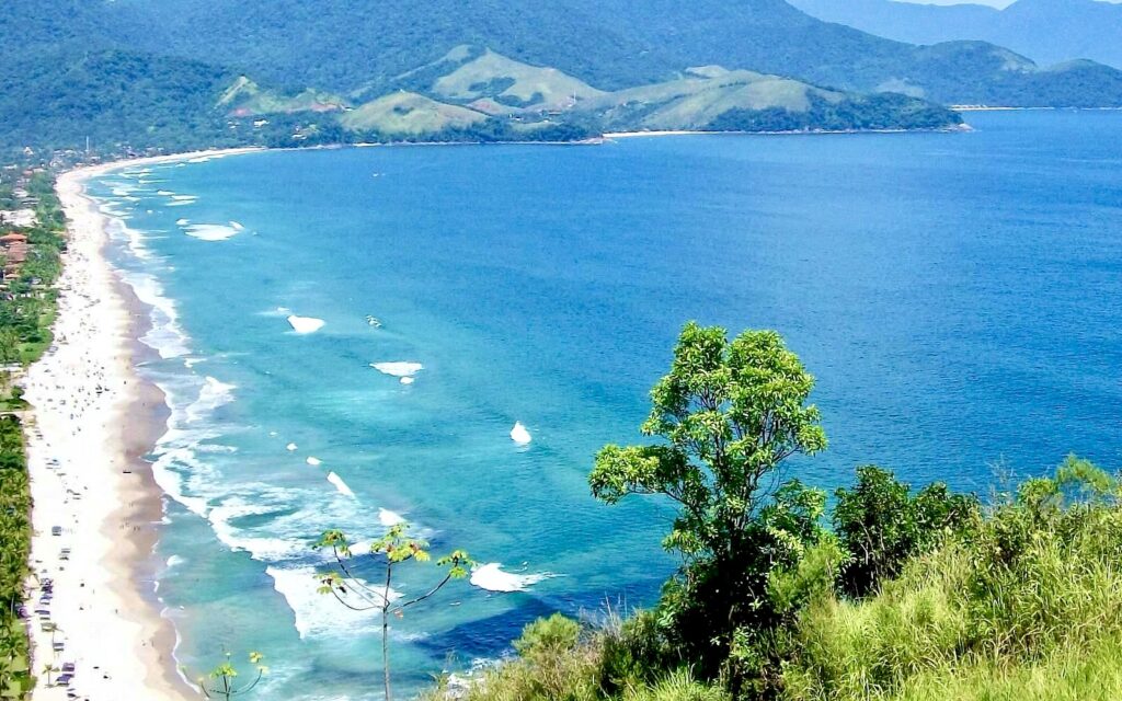 A stunning view of Maresias beach, known for its golden sands, clear blue waters, and perfect waves for surfing, located in São Paulo, Brazil.