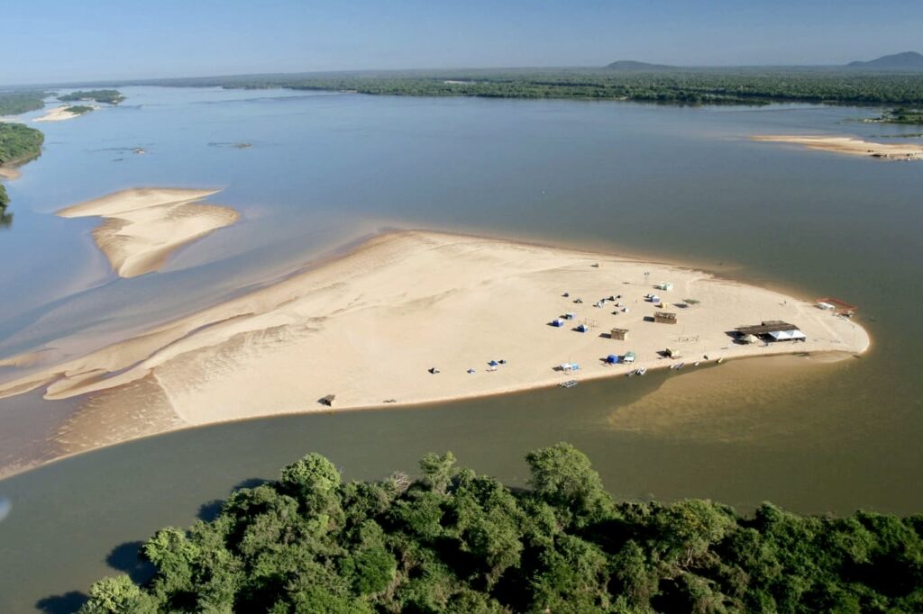 A serene view of Praia do Riko, with its golden sands and crystal-clear waters, located on the Araguaia River in Goiás, Brazil.