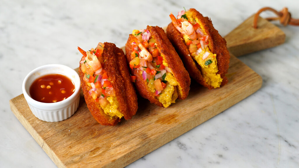 Acarajé, a traditional Brazilian street food from Bahia, made of black-eyed peas, deep-fried until golden, and served with shrimp, vatapá, and spicy sauce.