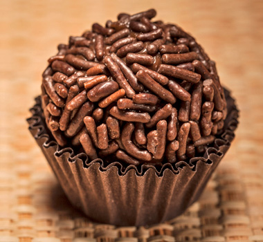 A close-up of Brigadeiro, Brazil’s beloved chocolate sweet, made with rich condensed milk and cocoa, rolled into a ball and coated with chocolate sprinkles.