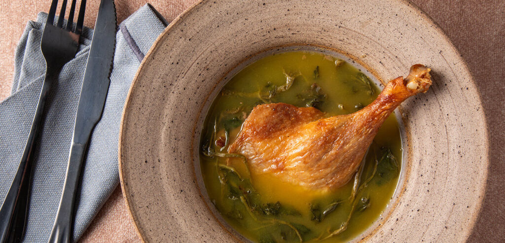 A steaming plate of Pato no Tucupi, a flavorful duck dish from the Brazilian Amazon, served with rice and infused with the unique taste of tucupi sauce.