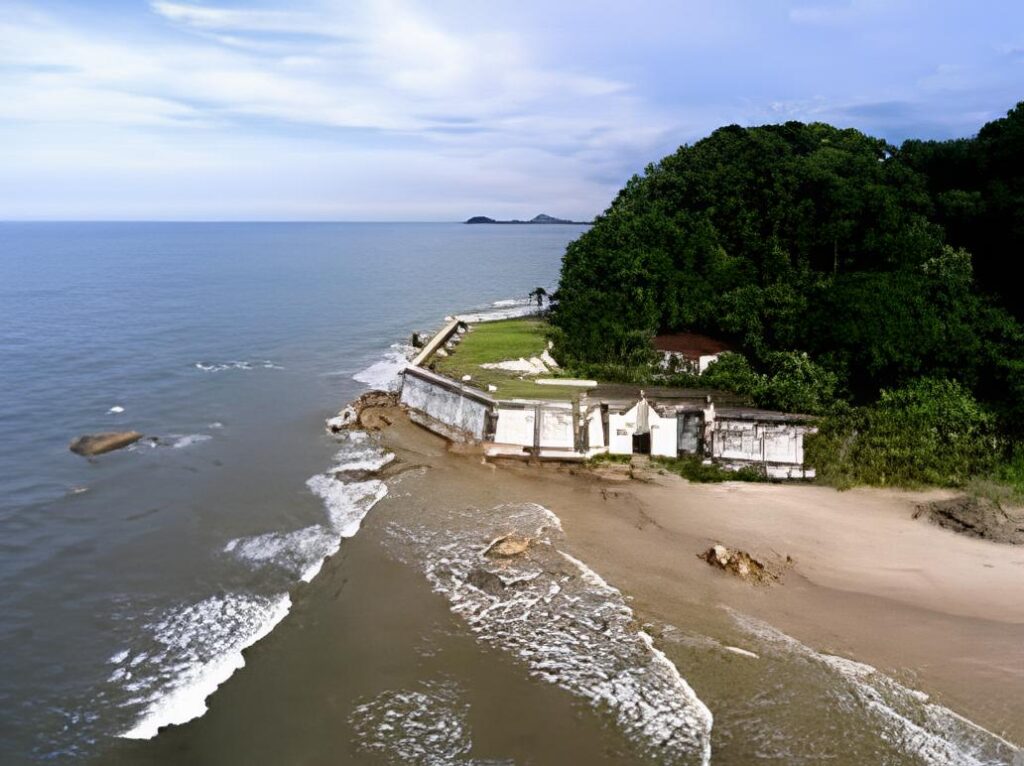 The stone walls of Fortaleza de Nossa Senhora dos Prazeres on Ilha do Mel, Brazil, standing against a backdrop of lush greenery and the sparkling blue sea."
