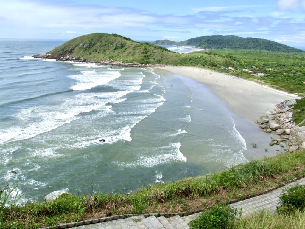 A stunning panoramic view of Praia de Fora on Ilha do Mel, Brazil, as seen from the top of Farol Hill, with golden sands meeting the turquoise ocean.