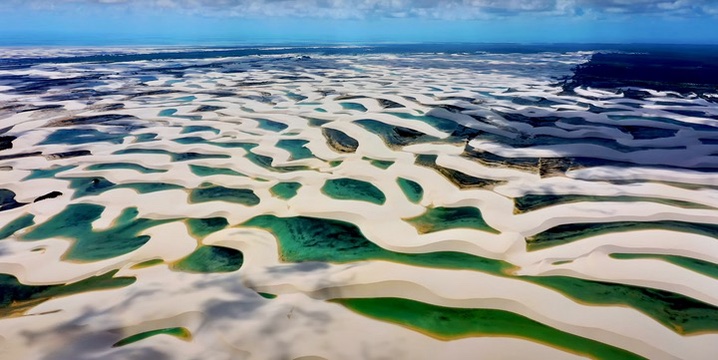 A breathtaking aerial view of Lençóis Maranhenses, showcasing the vast expanse of white sand dunes and turquoise lagoons stretching across the landscape.