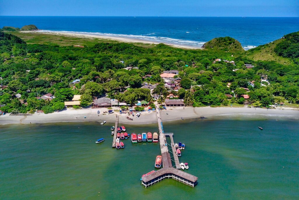 Aerial view of Encantadas Pier on Ilha do Mel, where boats dock against the backdrop of turquoise waters and charming coastal scenery.