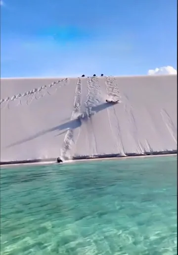 A traveler enjoys a refreshing swim in the crystal-clear waters of Lagoa Azul, surrounded by the stunning white sand dunes of Lençóis Maranhenses.