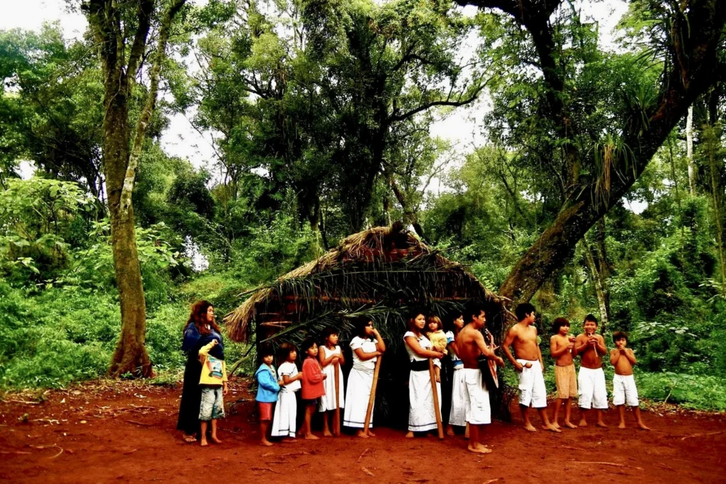 An image of Guarani tribe members wearing traditional attire, showcasing their cultural expressions near Iguazu Falls, representing the rich indigenous heritage of the region.
