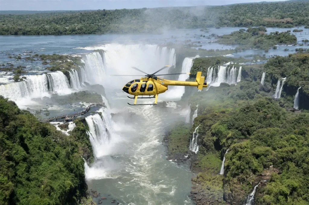 Helicopter flying above Iguazu Falls, offering a stunning aerial view of the cascades and surrounding rainforest.